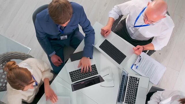 leaders analyze strategic documents together, corporate team discussing strategies over reports and laptops, executives and project manager collaborating during strategy meeting with reports