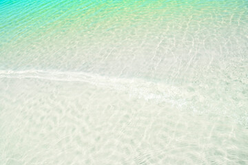 A background of clear water over a sandy bottom. Shallow water with clean sand. Gentle ripples on the surface. Glittering reflections on the sea.