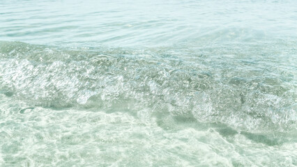 A background of clear water over a sandy bottom. Shallow water with clean sand. Gentle ripples on the surface. Glittering reflections on the sea.