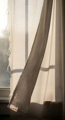 Close-up of sheer curtains gently billowing in the breeze near a sunlit window, creating a soft and tranquil atmosphere inside a cozy home