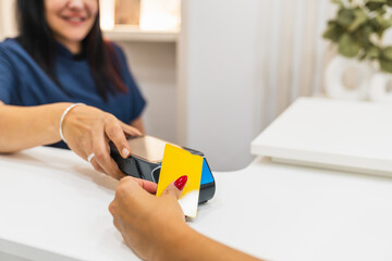 Clinic patient paying for services with a yellow credit card using a nfc terminal. Transaction at reception desk