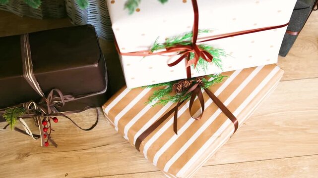 Elegant wrapped gifts with festive bows and pine sprigs on a warm wooden floor.