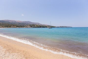 Obraz premium Crystal clear turquoise waters meet golden sandy beach with lush green hills .