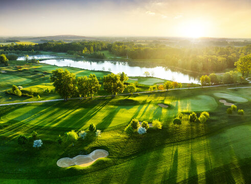 Aerial view of sunset over golf course with spring colored trees and lakes