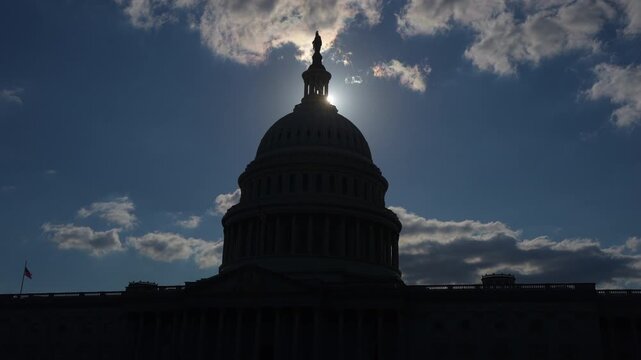 Capitol silhouette at sunset. Dramatic Washington skyline. US Capitol evening scene. Political landmark in low light. Capitol dome dusk view.