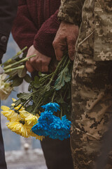 Ukrainian army. Memory of the dead. Russian-Ukrainian war. Ukrainian soldiers. Flowers in a man's hand. Honoring the memory. Posthumous ceremonies. Funeral bouquet. Military brotherhood.