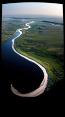An aerial perspective showcases a deep blue river meandering through a lush green, flat landscape with a prominent sandy bank.