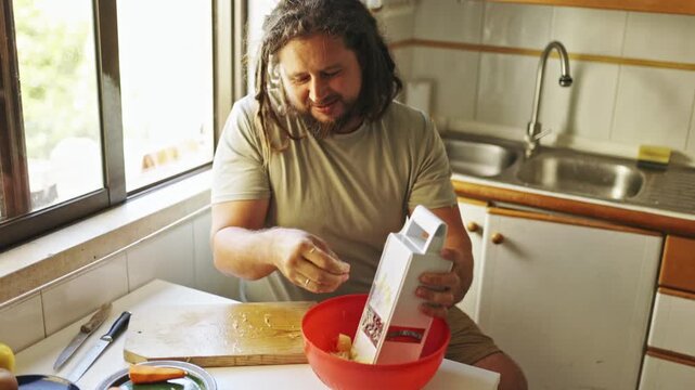 Man with dreadlocks grating potatoes in the kitchen