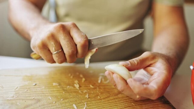 Male hands peeling garlic on a wooden cutting board