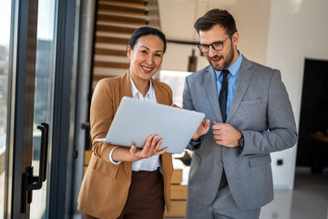 Two happy diverse multiethnic business team people working, talking in corporate office