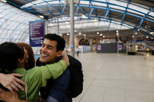 Happy friends hugging in train station during joyful reunion