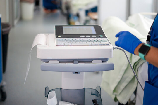 Nurse operating medical ecg machine in hospital hallway