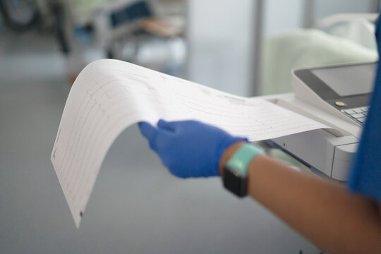 Healthcare professional holding ekg paper with heart data