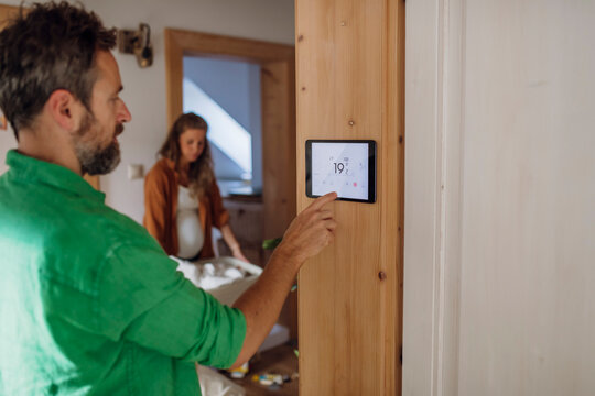 Mature man adjusting temperature through home automation app on tablet PC in attic