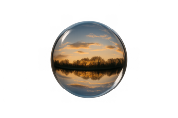 Glass sphere reflecting vibrant sunset landscape with trees and water, crystal ball showing an inverted natural horizon