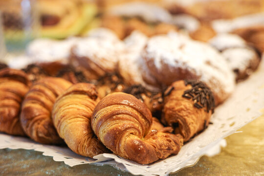 Assorted croissants and traditional ensaimadas on bakery tray