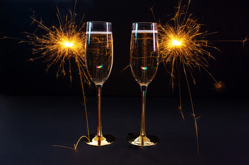 Happy New Year 2026, New Year's Eve holiday greeting card celebration. Sparklers firework, champagne glasses on black background