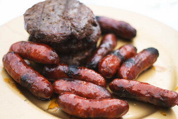 Fototapeta premium Grilled chorizos and hamburgers served on rustic plate