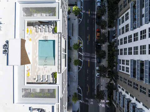 Aerial view of a turquoise swimming pool nestled between modern buildings, casting a stark contrast against the urban landscape, Edgewater, Miami, United States.