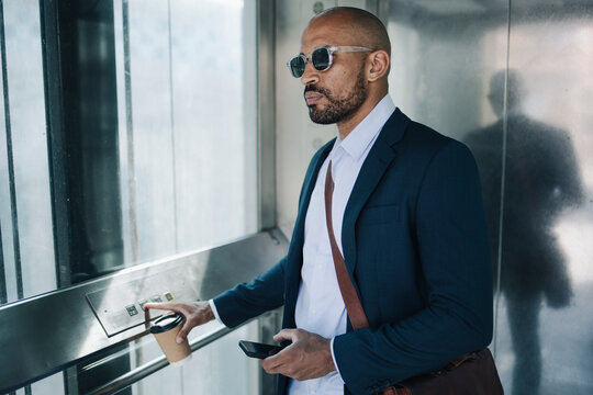 Businessman pushing button in elevator