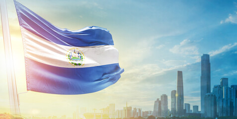El Salvador flag wavering in beautiful clouds with building skyline. The flag with drone shot in...