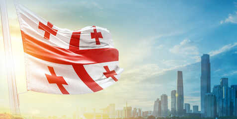 Georgia flag wavering in beautiful clouds with building skyline. The flag with drone shot in beautiful sky. Georgia national flag for independence day.