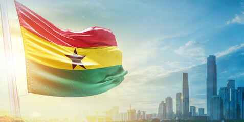 Ghana flag wavering in beautiful clouds with building skyline. The flag with drone shot in...