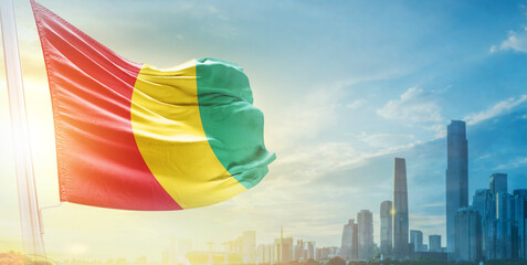 Guinea flag wavering in beautiful clouds with building skyline. The flag with drone shot in...