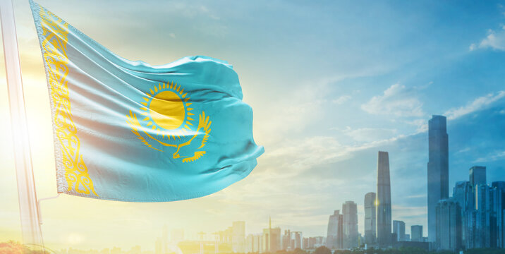 Kazakhstan flag wavering in beautiful clouds with building skyline. The flag with drone shot in beautiful sky. Kazakhstan national flag for independence day. - Powered by Adobe