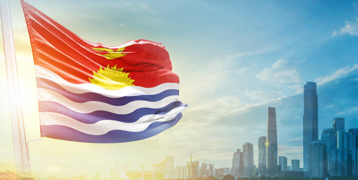 Kiribati flag wavering in beautiful clouds with building skyline. The flag with drone shot in beautiful sky. Kiribati national flag for independence day.