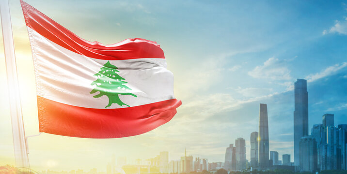 Lebanon flag wavering in beautiful clouds with building skyline. The flag with drone shot in beautiful sky. Lebanon national flag for independence day.