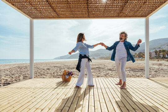 Happy senior couple enjoying dance in gazebo at beach
