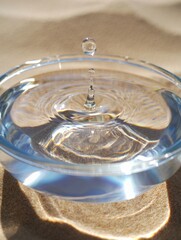 Water droplet creating ripples in a shallow blue bowl