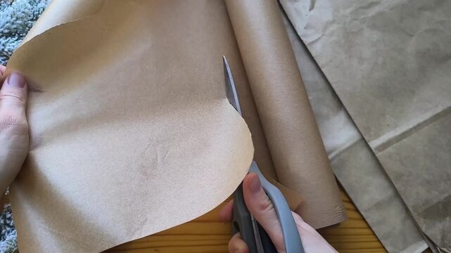 Scissors cut a piece of kraft paper from a roll. Eco-friendly gift wrapping materials for Christmas 