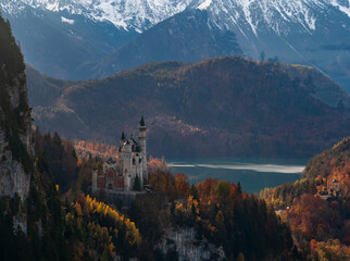 Neuschwanstein Castle in the autumn sun, amidst the stunning mountain scenery.