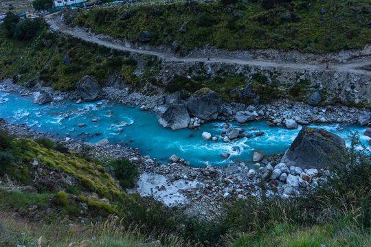 Stunning turquoise-blue glacial river Alaknanda flowing over rocks and boulders in Mana Village