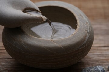Hands shaping clay in a pottery studio on a wooden surface
