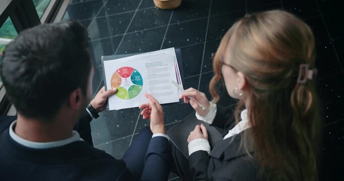 Businesswoman Pointing To A Section Of The Pie Chart With A Pen, Discussing Data Analysis, Business Strategy To Her Colleague. - high angle shot