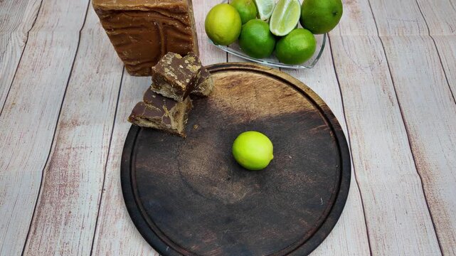 Man's hand spinning a fresh lime on a wooden board to get more juice for a drink