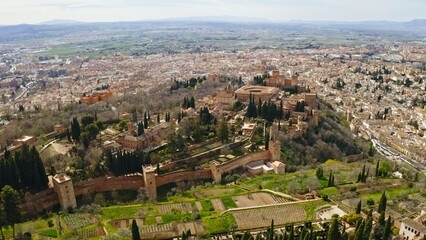 Aerial view historical Alhambra Palace at sun surrounded by Sierra Nevada mountains in Granada...