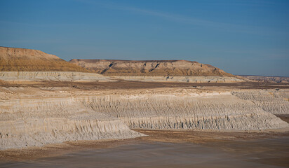 vast landscape with white limestone cliffs and dry riverbed in a remote desert region, under a clear blue sky, showcasing layered rock formations and arid terrain