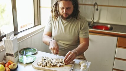 Man with dreadlocks cutting fresh mushrooms - Powered by Adobe