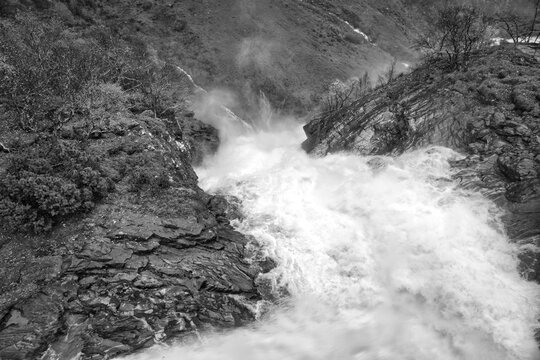 Dynamic waterfall in a rocky autumn landscape with bubbling water. Black, white