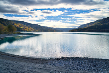 Reflecting lake under dramatic sky in autumnal natural scenery