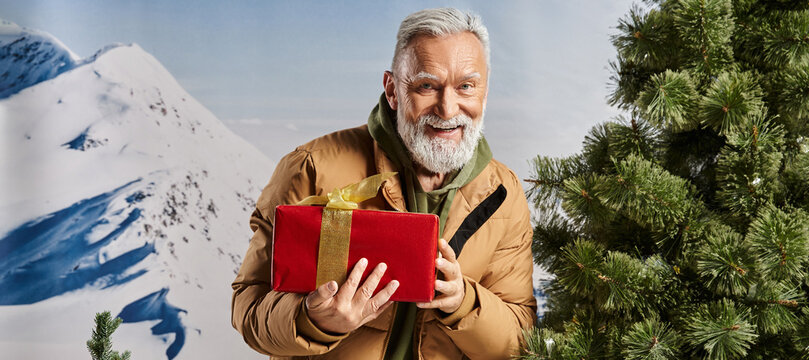 Festive winter joy with a charming senior man holding a gift in a snowy landscape