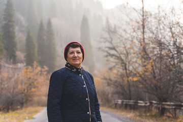 Portrait of senior woman walking in misty autumn mountain forest