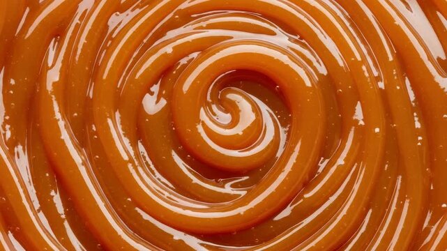 Delicious golden caramel syrup forming intricate swirling patterns. This rich, tempting texture is perfect for culinary themes and sweet dessert advertising