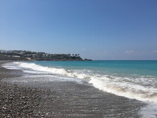 Tranquil Seaside Landscape with Gentle Waves and Clear Blue Sky near Rocky Shoreline