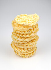 A tower made of corrugated corn chips on a white background. Round corn chips.
