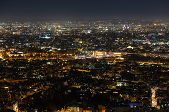 Aerial view of shimmering lights blanket the cityscape, a radiant tapestry woven across the night, illuminating iconic landmarks, Paris, Ile-de-France, France.